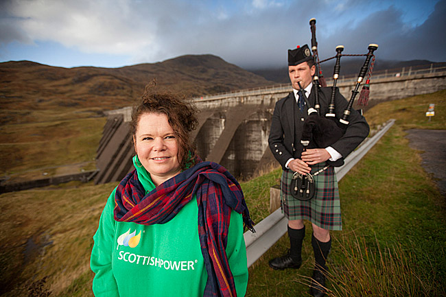 Jacqueline Kay, wearing checks, with a ScottishPower piper at Cruachan Power Station.