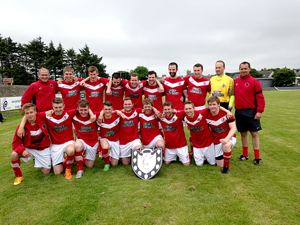 Orkney's players and staff celebrate with the Archer Shield at an overcast Dammies pitch